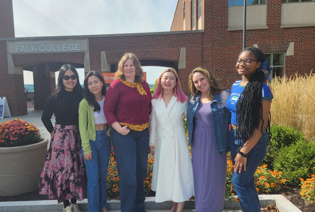 Photo of lab members outside the Falk College building.
